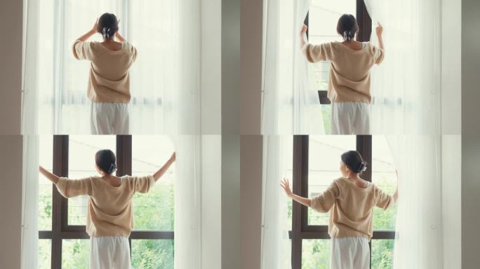 快乐的亚洲女孩与白色的奶油睡衣打开白色的窗帘在窗户上看外面感觉清新与宁静的早晨和新鲜的空气在周末在家