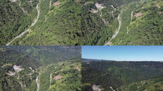 在墨西哥普埃布拉，无人机拍摄了一条河流和一条穿过山景的狭窄道路，背景是萨卡特兰市