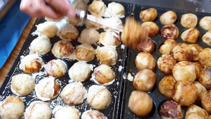 烹饪刚做的章鱼烧日本章鱼球，近距离观察日本流行的街头小吃在热盘子上滋滋作响