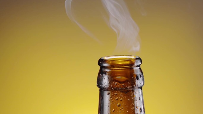 用开瓶器打开啤酒瓶，瓶盖飞向背景，啤酒气体的冷凝物从瓶口处上升。