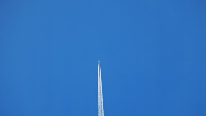 飞机在万里无云的蓝天中直线飞行，留下白色的蒸汽痕迹和大量的复制空间