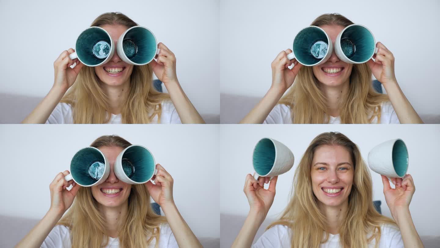 一个美丽的年轻女孩通过咖啡杯临时制成的双筒望远镜看到了她光明而有趣的未来