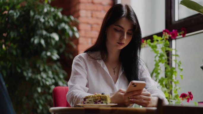 年轻漂亮的成年女性在咖啡馆休息，用智能手机聊天