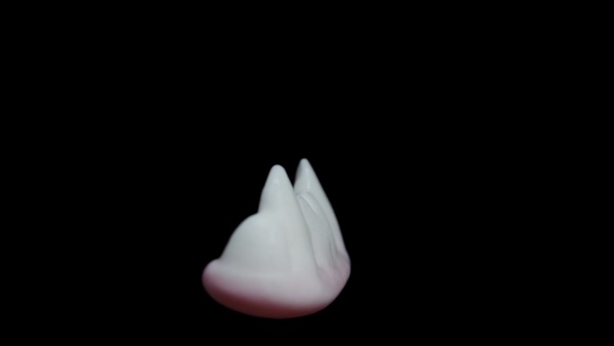 在一个特写镜头中，一个形状像白色牙齿和吸血鬼尖牙的软糖，在黑色背景上旋转，孤立的。