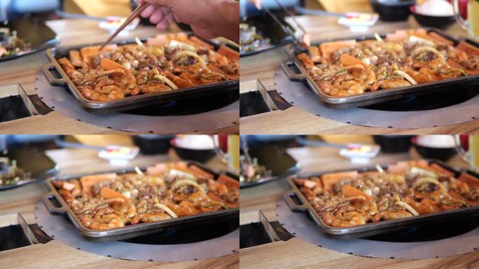 日本美食美味的日式涮锅和烧烤盘或烧烤盘。火锅涮的特写，用筷子夹肉、牛肉片放入火锅锅中烹煮。
