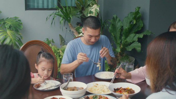 亚洲家庭吃中国菜，坐在后院的餐桌上玩得很开心。多代同堂的家庭一起享受消费。