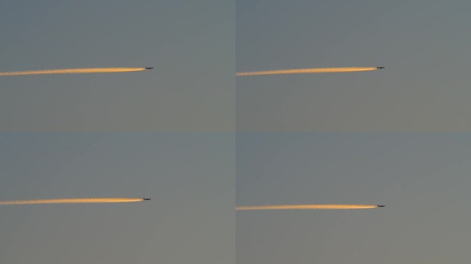 黎明时分飞行的飞机带着橙色的尾迹