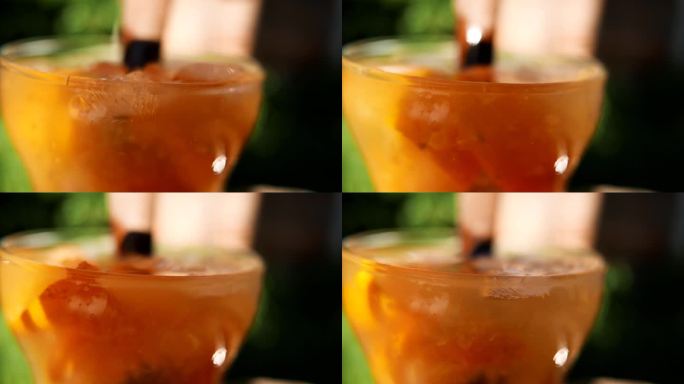 调制凯皮林纳鸡尾酒。一个人在调制凯匹林纳酒的特写镜头。搅拌橘色凯匹林纳鸡尾酒。使用木制搅拌器。用甘蔗