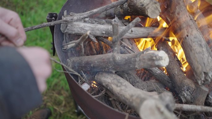 一个面目全非的人正在烧木炭烤炉里的木头做午饭