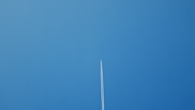 孤独的飞机留下蒸汽的痕迹，而直接移动在蓝天与大量的复制空间