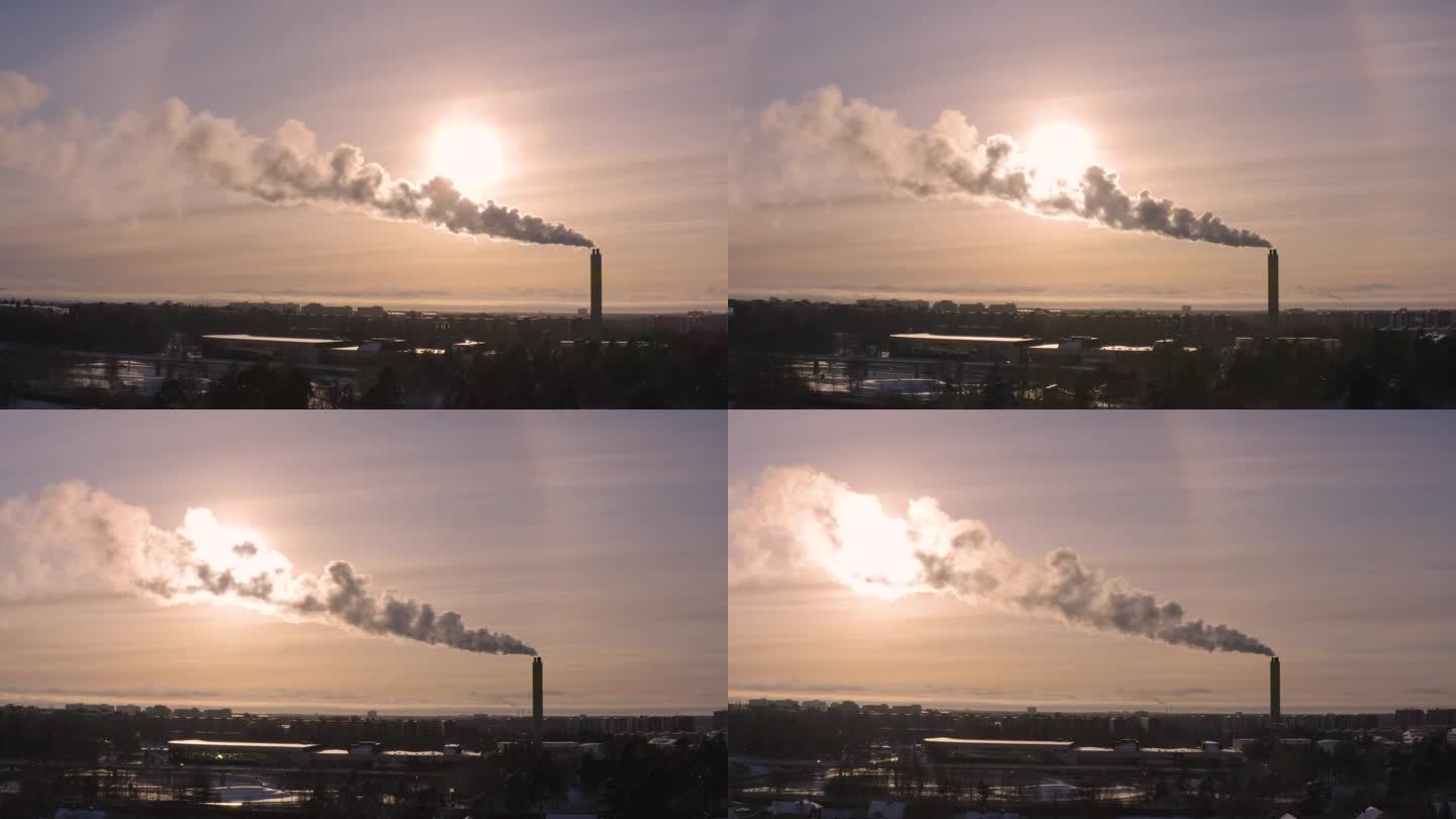 无人机拍摄的画面显示了区域供热厂的烟雾和冬季日落的相互作用，为白雪覆盖的居民区蒙上了阴影。