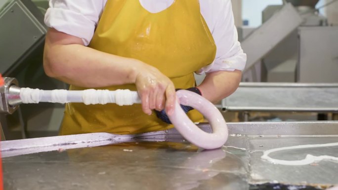 在肉制品厂，女工正在把香肠包装成天然肠衣。