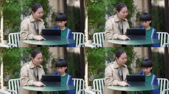 年轻的母子在院子里用平板电脑看书