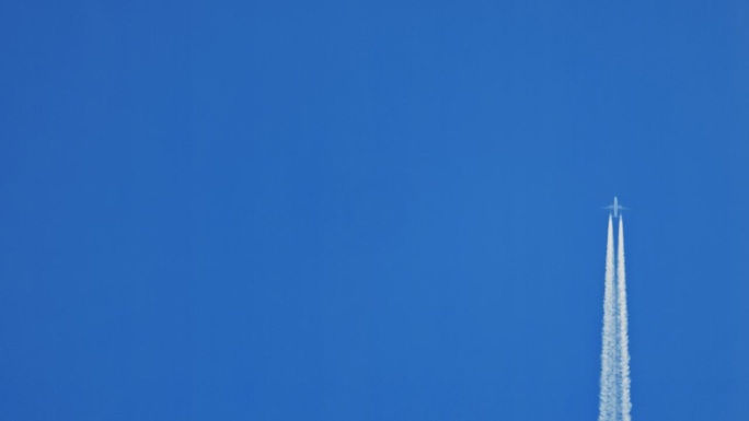 飞机在无云的蓝天中飞行时留下白色的蒸汽痕迹，有很多复制空间