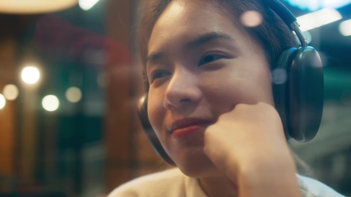 快乐的年轻亚洲单身女性戴着耳机听着音乐，快乐的女性在现代咖啡站放松假期