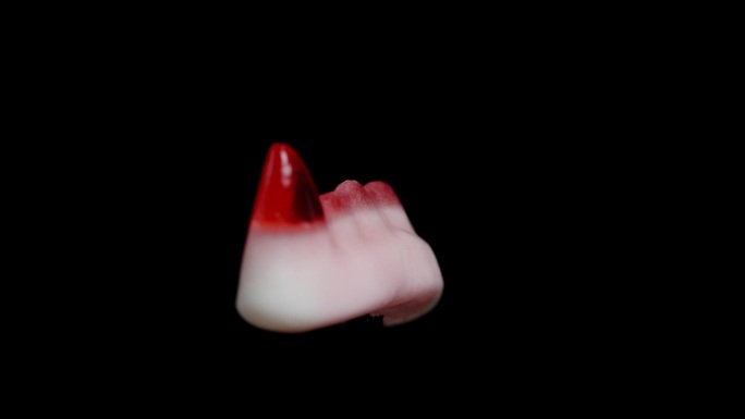 有嚼劲的软糖，形状像红色的吸血鬼尖牙，旋转着。孤立在一个黑色的背景。