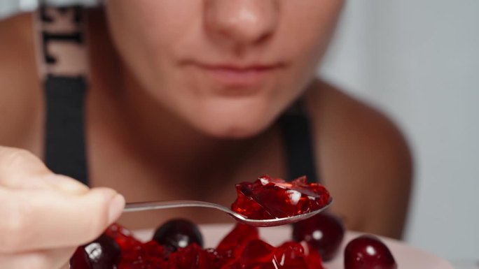 一个年轻女子吃着红色的樱桃果冻，慢镜头，特写镜头。