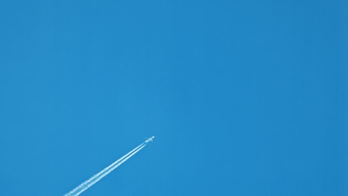 飞机的正下方在清澈的蓝天中留下水汽的痕迹和复制空间。飞机飞行