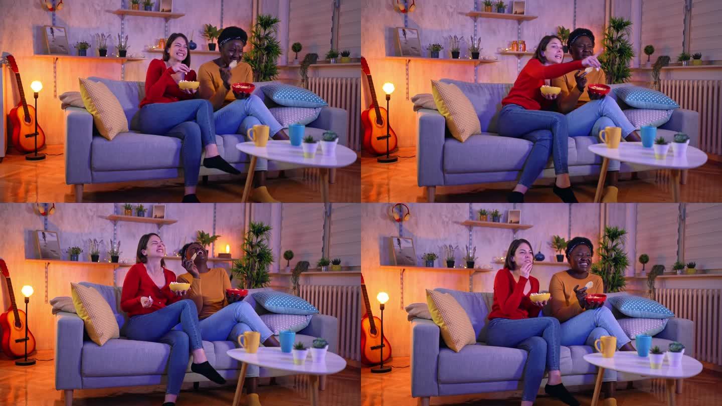 女性朋友坐在沙发上吃零食，一起看喜剧电影
