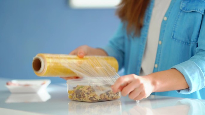 妇女用食品薄膜包装食物，以便在冰箱中储存
