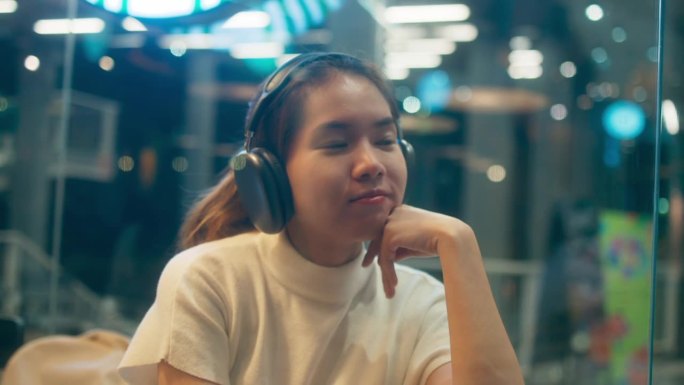 快乐的年轻亚洲单身女性戴着耳机听着音乐，快乐的女性在现代咖啡站放松假期