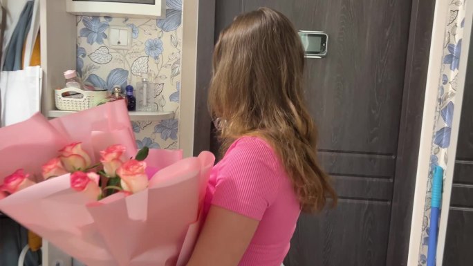 国际祝贺机构送花的年轻女孩打开门迎接信使带着一束生日快乐幸福玫瑰粉红色的家居摆设