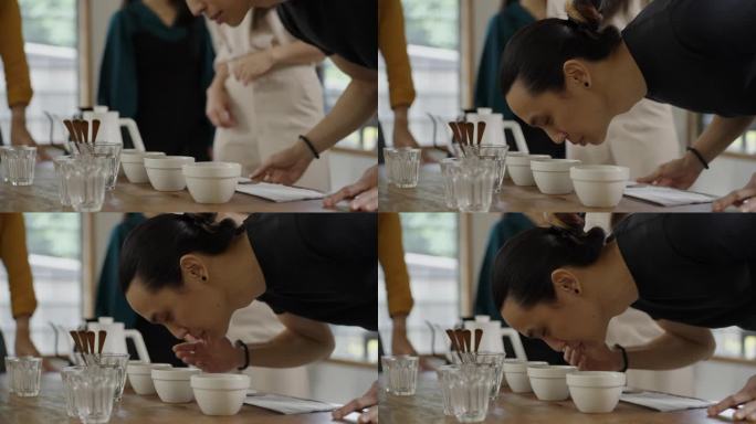亚裔华裔男咖啡师舀咖啡渣清洗杯饮范围，从桌上的陶瓷杯上撇去咖啡渣-库存视频