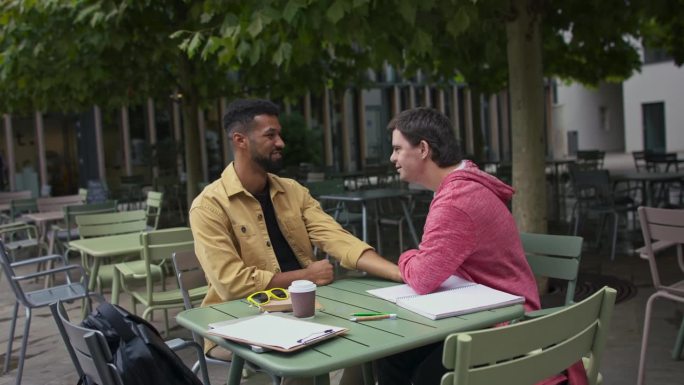 一个患有唐氏综合症的年轻人和他的导师朋友在咖啡馆里掰手腕。