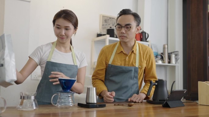 亚洲华人男咖啡师咖啡馆老板正在和他的员工进行冷萃咖啡滴滤训练