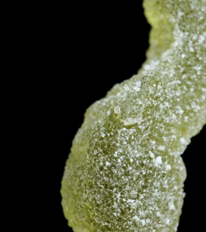 虫糖一种粘在上面撒有糖的蠕虫或幼虫形状的软糖在一个特写镜头中，它在黑色的背景上旋转，孤立的。