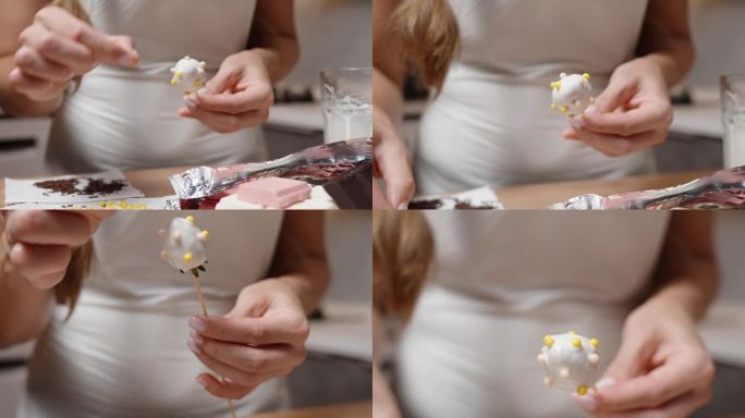 镜头慢慢拉近，这位女士用白巧克力把草莓装饰成五颜六色的糖球。