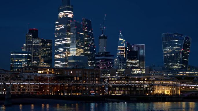 伦敦市中心的夜景，英国。市区的摩天大楼，泰晤士河上的千年桥，灯光明亮。慢动作