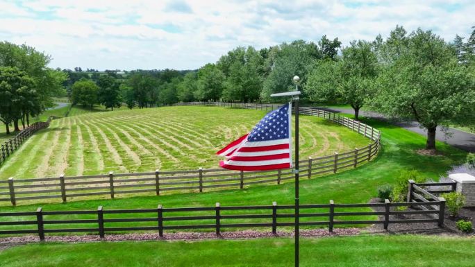 美国国旗在牧场的围栏前飘扬。航拍拍摄。