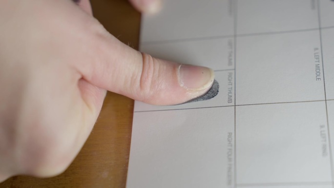 文件侧视图上的拇指指纹，靠近墨垫上的拇指指纹