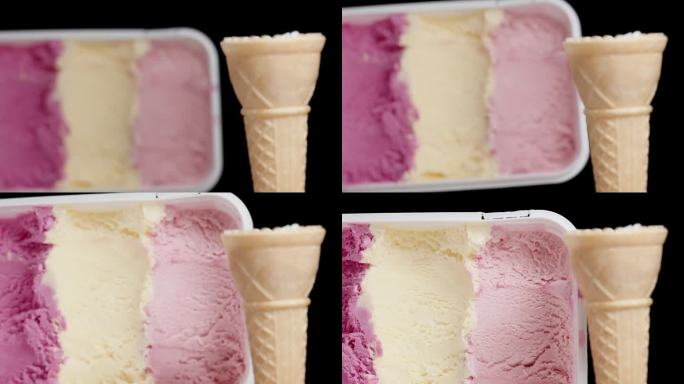一个空的华夫蛋筒和一盒黑色背景的彩色粉色冰淇淋。