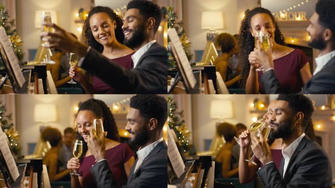 夫妇坐在钢琴前庆祝圣诞或新年聚会，一起喝香槟