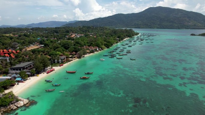 丽贝岛的泰国海岸线上，有船只和酒店，阿当岛在背景中飞来飞去
