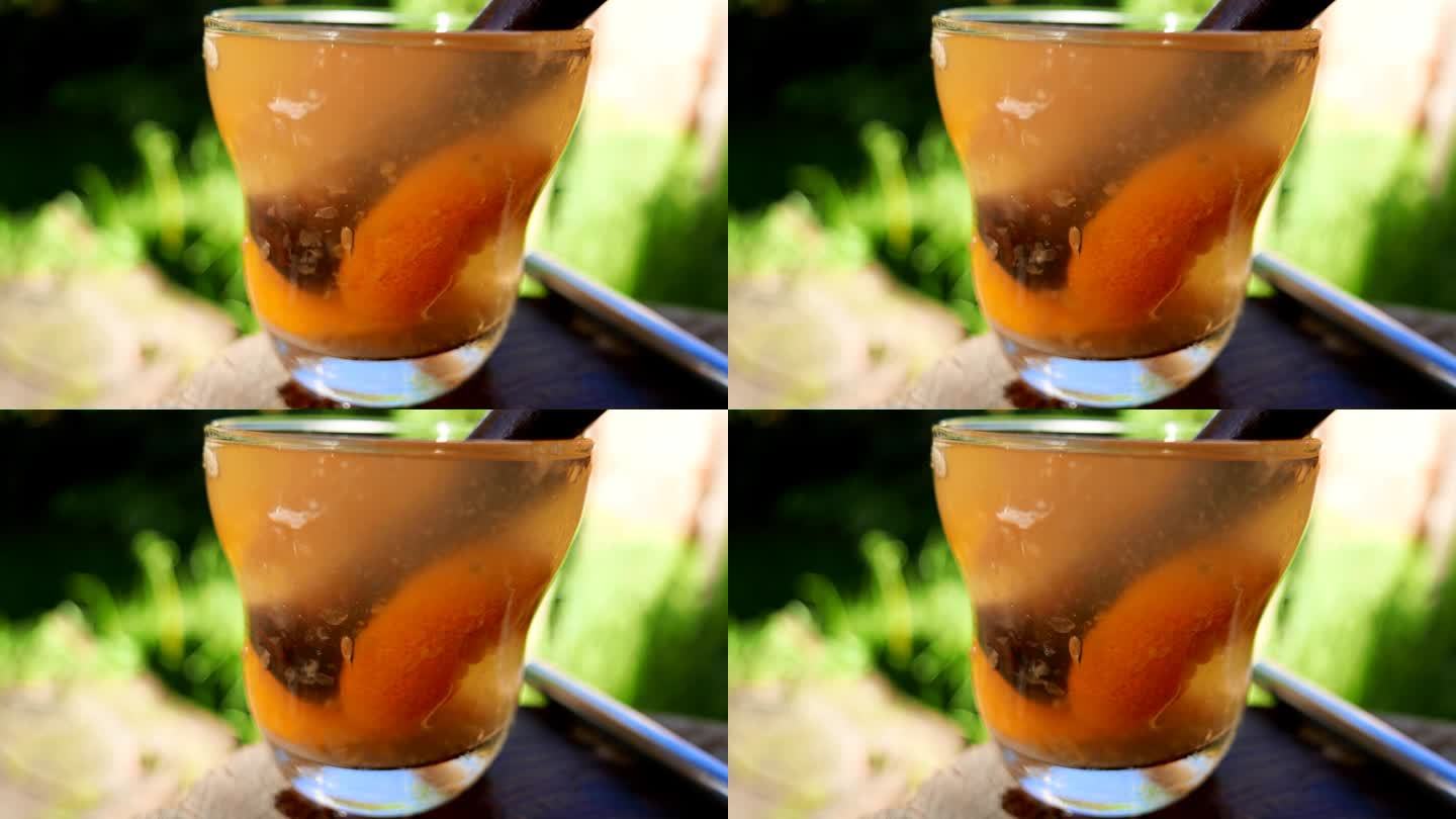 近距离拍摄的巴西凯匹林纳酒在桌子上，在阳光下，在后院。调制凯皮林纳鸡尾酒。搅拌橘色凯匹林纳鸡尾酒。使