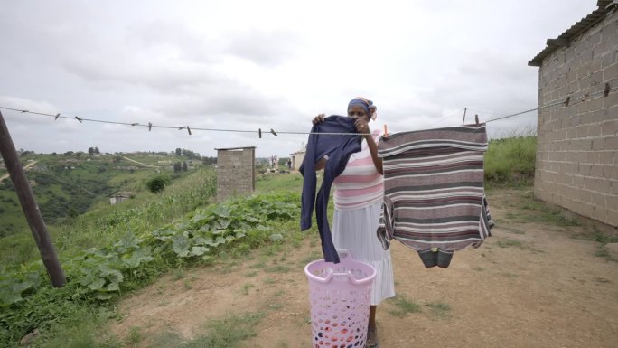 一位非洲妇女在农村农场晾衣服。