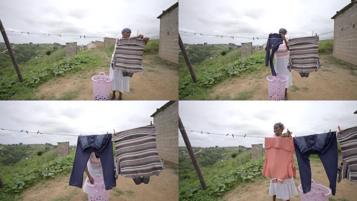 一位非洲妇女在农村农场晾衣服。