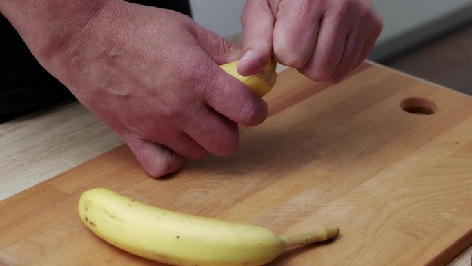 厨房里一个男人用手剥香蕉的特写。
