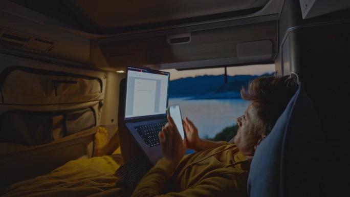 自由职业者靠在露营车上用笔记本电脑工作
