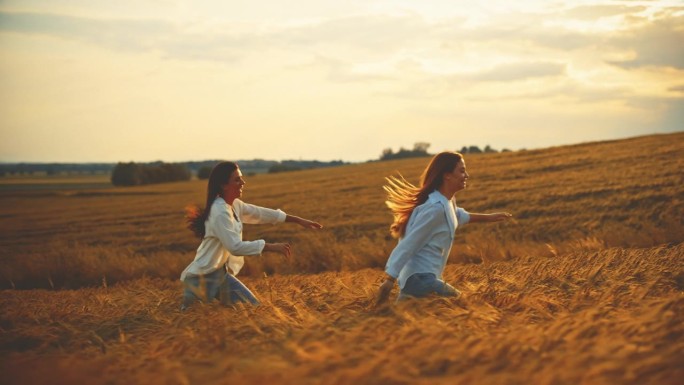 在假期的夕阳下，快乐的女性朋友在田野里玩耍