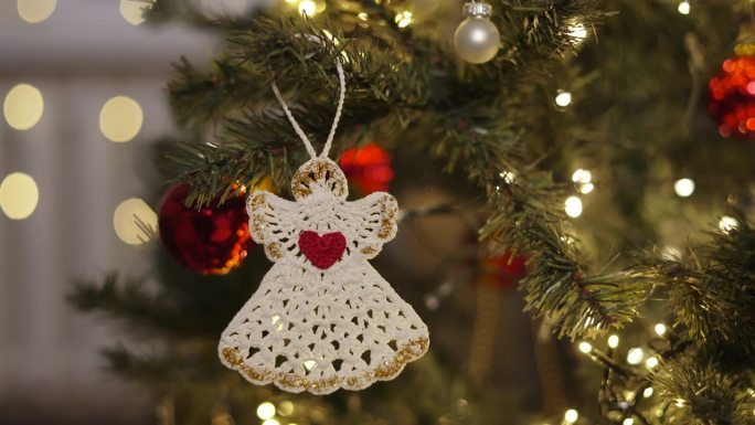 生态编织装饰形式的白色天使抱在圣诞树上。