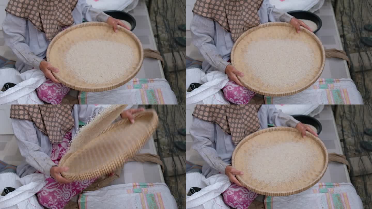 女农民在碾磨后用竹盘清洗稻谷