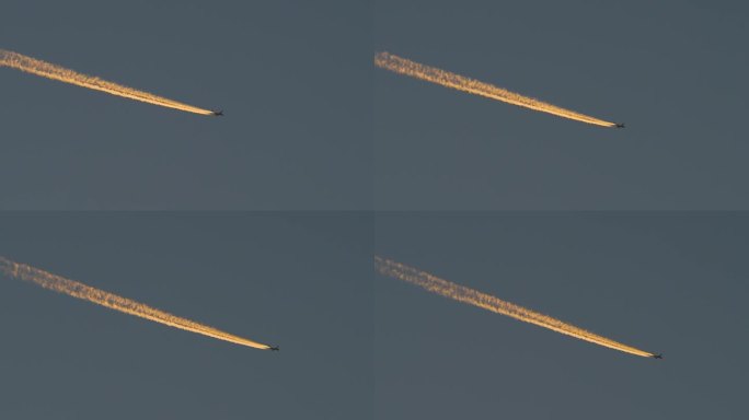 黎明时分飞行的飞机带着橙色的尾迹