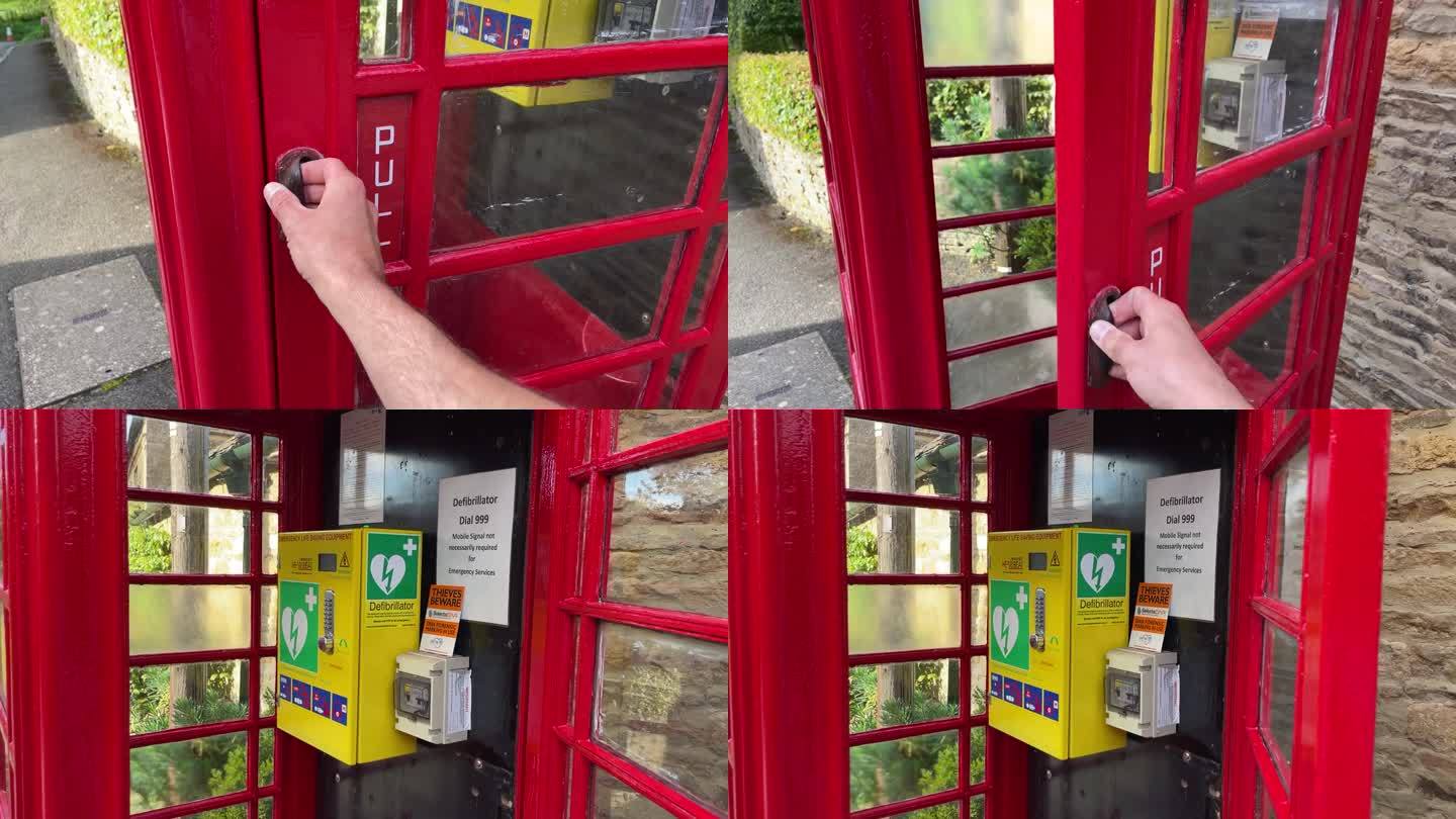 在英国，一个男人的手打开了一个红色电话亭的门，这个电话亭被改造成了一个除颤器亭。