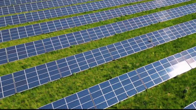 在绿色草地上排成一排的面板。太阳能转换系统。太阳反射在电池板上。清洁技术创造更美好的未来。