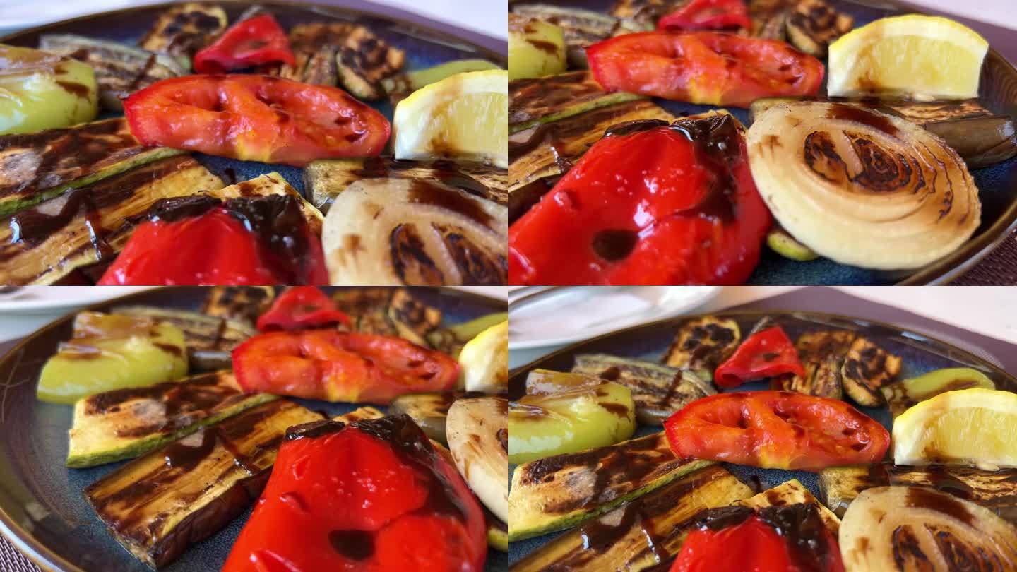 在浅灰色石板、石头或混凝土的背景上，盘子里烤着五颜六色的蔬菜甜椒、西葫芦、茄子。带复制空间的俯视图。
