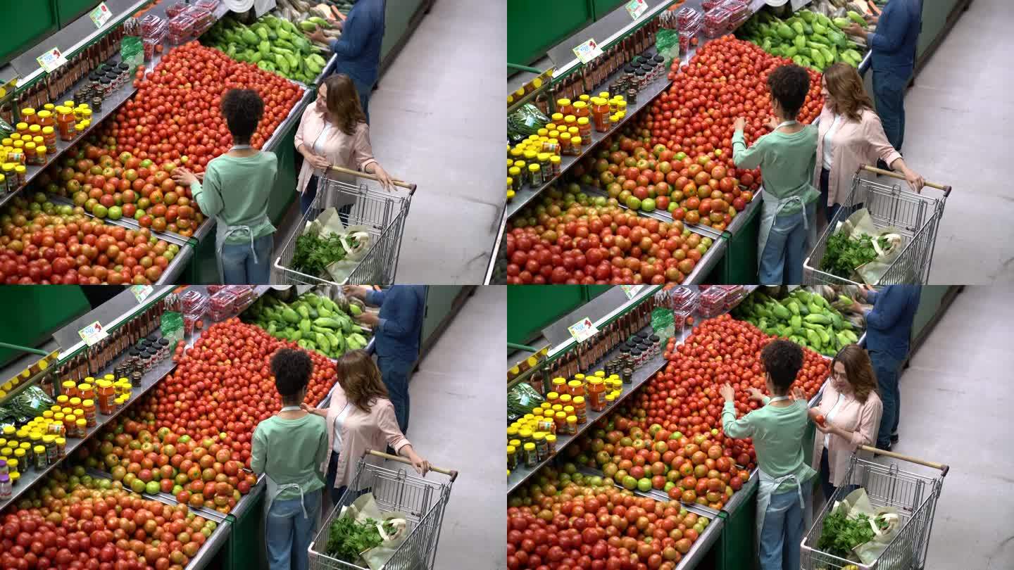 成年女性顾客在蔬菜水果店购物，向友好的售货员询问选择西红柿的建议